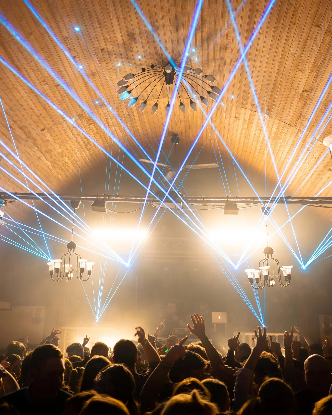 Hell erleuchteter Raum mit hellblauen Laserstrahlen. Raum mit Crowd gefüllt.