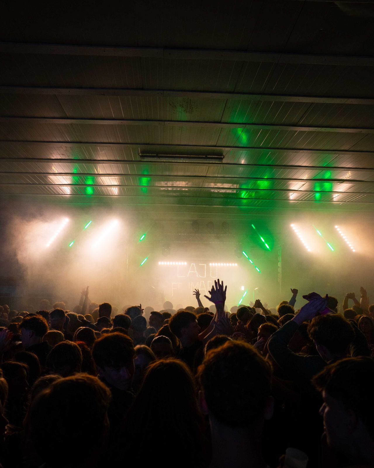 Halle hell erleuchtet mit Crowd im Vordergrund und Bühne im Hintergrund.