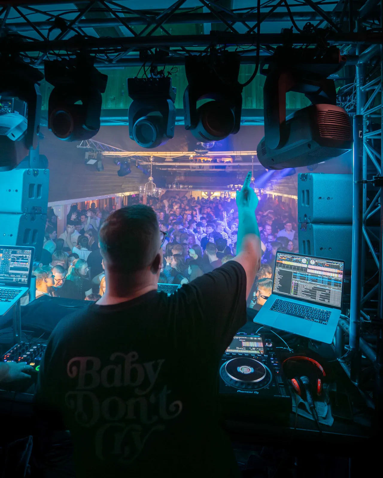 Daniel Mic auf der Bühne mir einem Arm in der Luft. Im Hintergrund ist die Crowd im blauen Licht zu sehen.