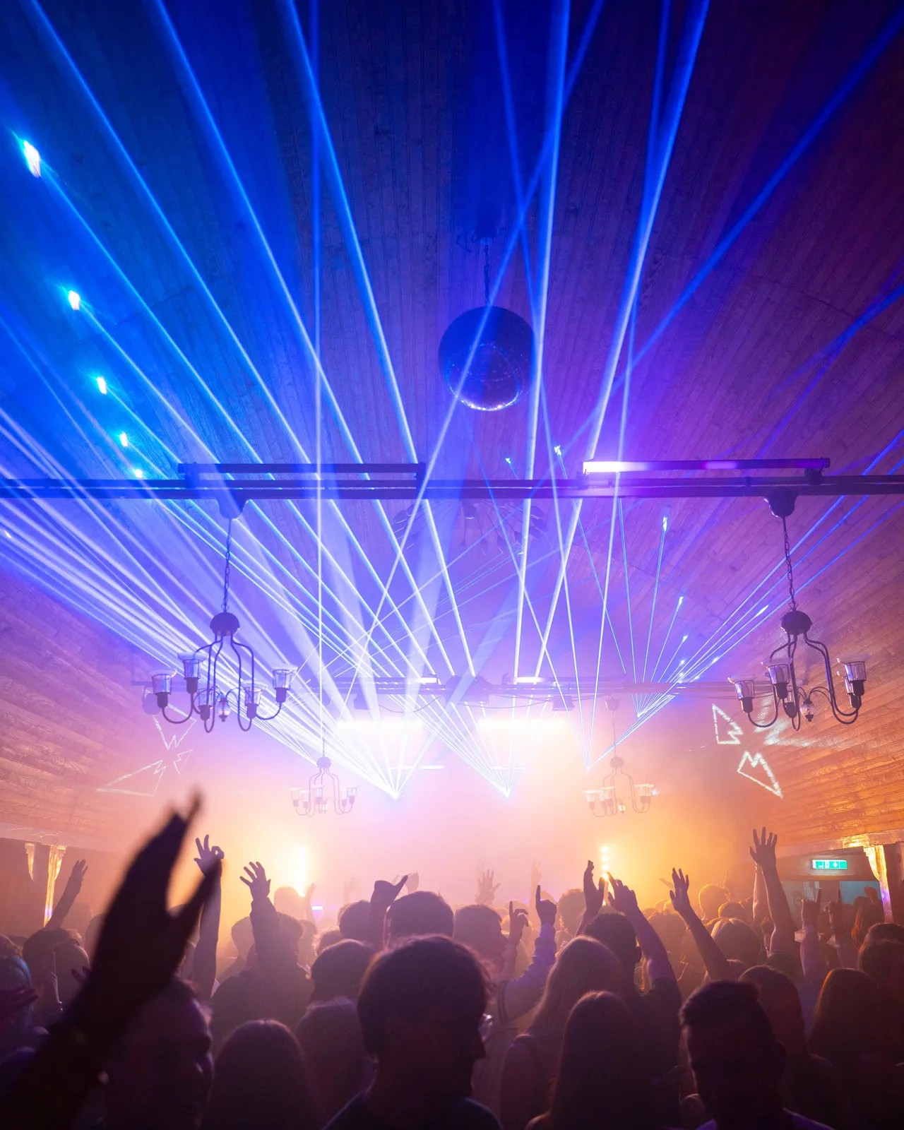 Hell erleuchteter Raum mit blauen Laserstrahlen über der Crowd.
