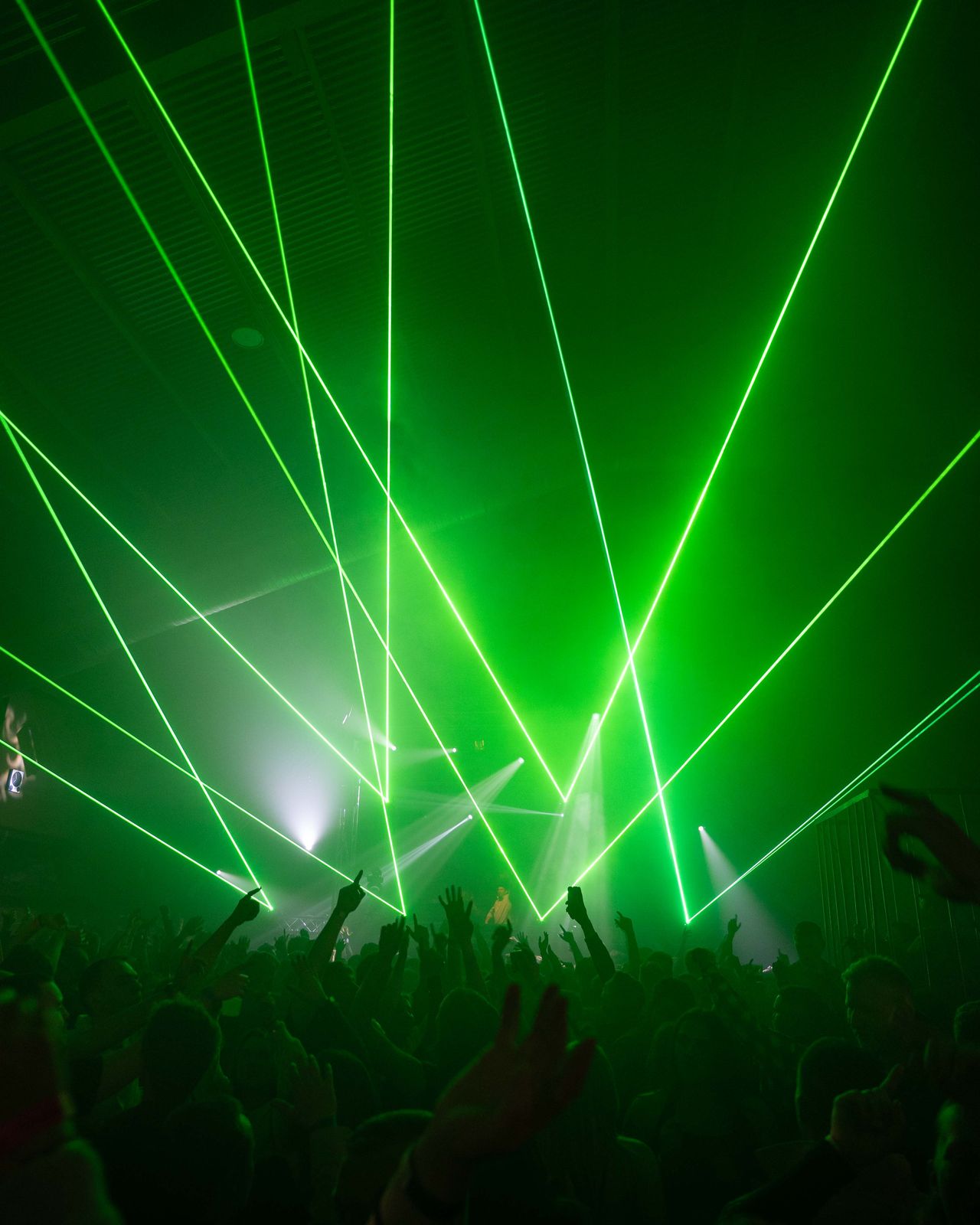 Grüne Laserstrahlen über Crowd, die Hände hochreißt.