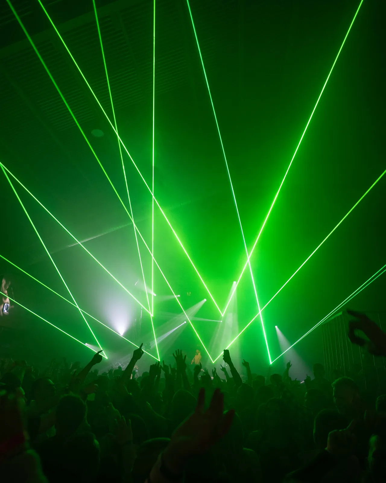 Grüne Laserstrahlen über Crowd, die Hände hochreißt.
