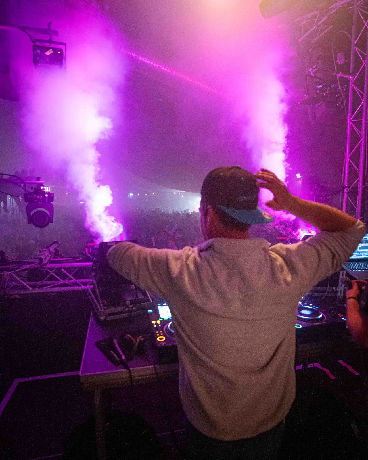 Soeren Hartmann am DJ Pult auf der Bühne mit Fog Jets, die Nebel abfeuern, im Hintergrund.