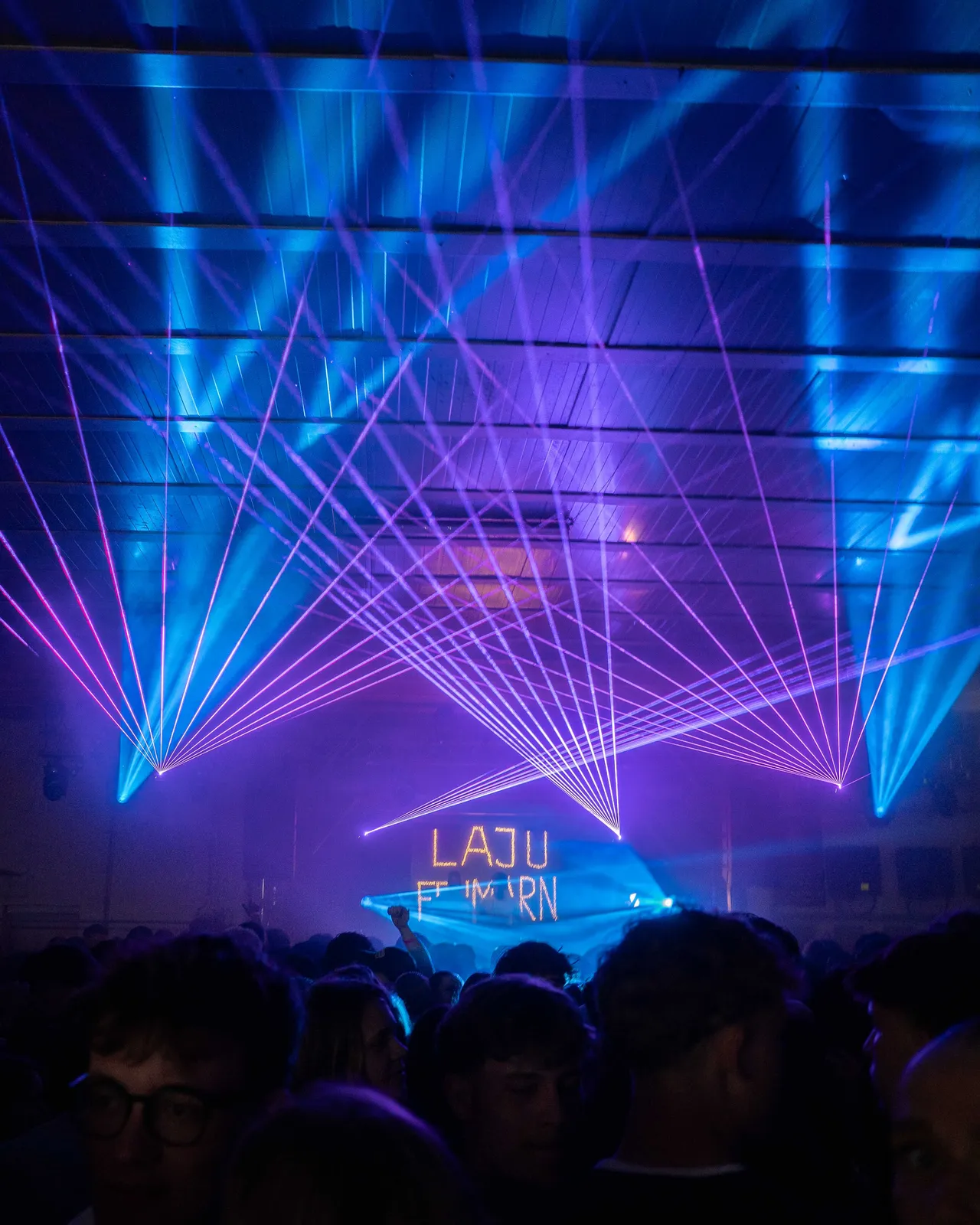 Blaues Licht und lila Laserstrahlen kommen von der Bühne.